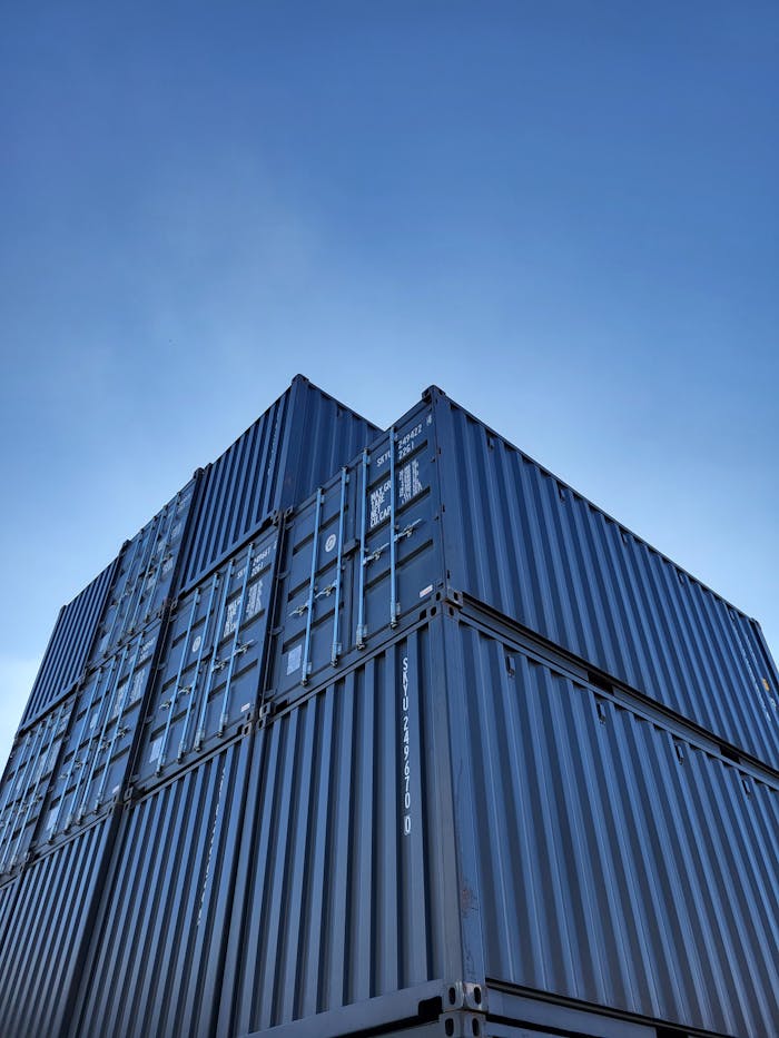 Low angle view of stacked cargo containers with clear blue sky background.